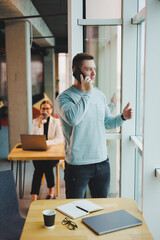 Business man, manager looking out of window in deep thought, standing at workplace with phone in office, thinking about future of company, thinking about solution for work task