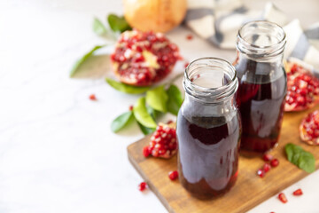 Pomegranate juice in glass bottles and fresh pomegranate fruits. Healthy drink diet immunity vitamins or vegetarian food concept. Copy space.