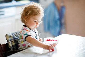 Adorable baby girl eating from spoon fresh healthy raspberries food, child, feeding and development...