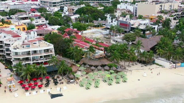 tropical beachfront hotels with umbrellas on white sand beach of Playa Del Carmen, aerial