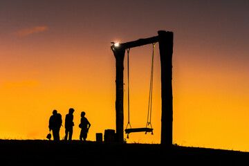 silhouette of happy young man and woman on hadubi hill and a swing with golden light sunset background. Hadubi viewpoint at Lao Wu village ,Wiang Haeng, Chiang Mai, Thailand.Copy space for inscription