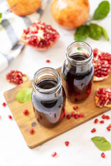 Pomegranate juice in glass bottles and fresh pomegranate fruits. Healthy drink diet immunity vitamins or vegetarian food concept.