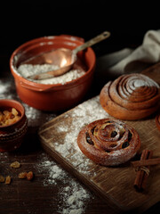 Homemade Swedish buns, fika. Fresh pastries, flour and rolling pin on a dark wooden background