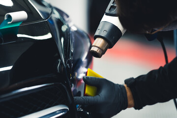 Process of car detailing - automotive lamps tinting done by an expert in protective gloves with the...