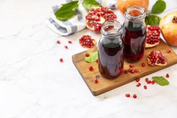 Fototapeta na wymiar Healthy drink diet immunity vitamins or vegetarian food concept. Pomegranate juice in glass bottles and fresh pomegranate fruits. Copy space.