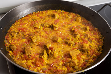 Pan with a meat paella about to be removed from the heat, close-up.