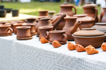 Defocus pottery from earthenware jugs mugs in nature. Set of old ceramic pot and mug, kitchen retro equipment of cooking on festival background. Ukrainian culture. Out of focus