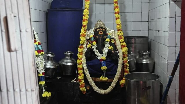 Closeup of lord ganesha decorated with garlands inside temple