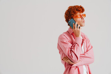 Young ginger puzzled man wearing shirt talking on cellphone