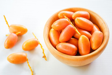 Fresh dates in a wooden bowl on a white table. Top view.