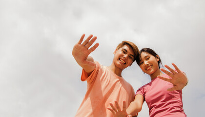 Portrait young asian girlfriend and boyfriend waving hello before exercising, playing sports together smiling at the camera in a good mood on a sunny day : Sports and recreation health concept.