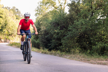 Obraz premium young cyclist riding relaxed with his mountain bike on a forest road, concept of freedom and sport in nature
