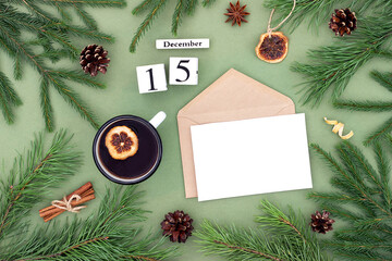 December 15. Calendar date, white blank with craft envelope, cup of tea and natural decor on green background. Hello winter. Template for your design, greeting card