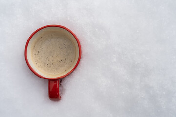 Red mug with coffee, cocoa or hot chocolate drink, in a deep fresh white snow. Warming beverage on a cold winter weather day. Flat lay composition with copy space.