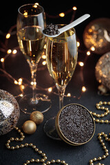 Black caviar in a mother-of-pearl spoon and jar and glass of champagne with Christmas decoration - obrazy, fototapety, plakaty
