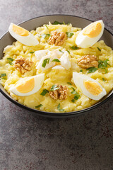 Spanish cuisine mashed potatoes with cod and garlic served with walnuts and boiled eggs close-up in a bowl on the table. Vertical