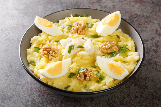 Delicious mashed potatoes with salted cod and garlic served with walnuts and boiled eggs close-up in a bowl on the table. Horizontal