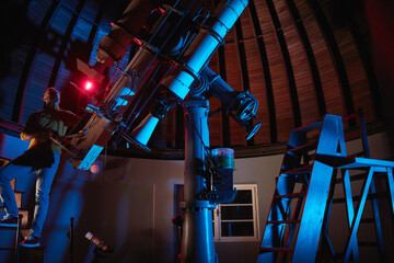 Astronomer with a big astronomical telescope in observatory doing science research of space and...