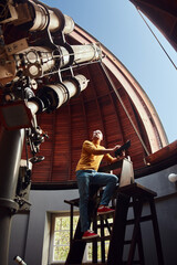 Astronomer with a big astronomical telescope in observatory doing science research.