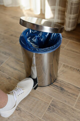 Close-up of the foot, pressing the pedal to open the lid of the trash can. Room cleaning.