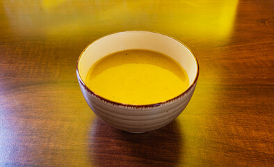 Small bowl of pumpkin cream soup on wooden table