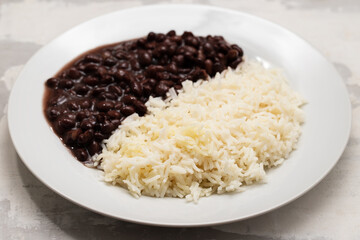 Black beans and boiled rice on white dish.