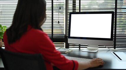 Rear view of female investor looking at computer screen, checking online information on personal computer