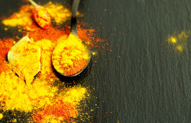 Turmeric and red sweet pepper are scattered on a dark background. Various spices.