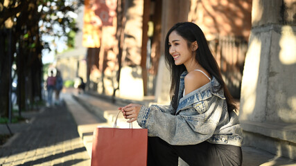 Fototapeta premium Portrait of modern fashionable women with shopping bags sitting on urban stairs shopping district of a city