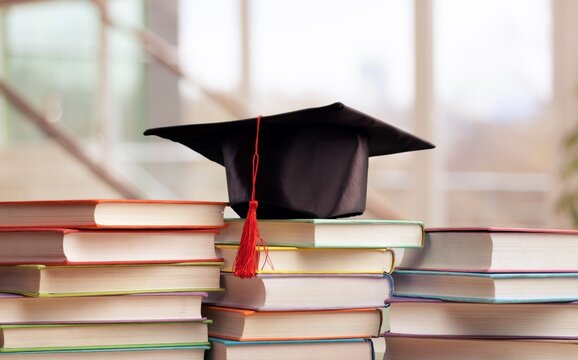 Graduation cap and stack of books on a table