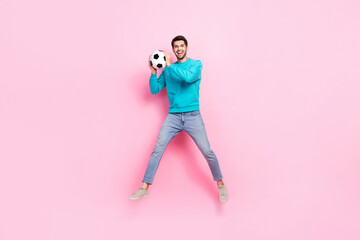 Fototapeta na wymiar Full size photo of handsome young man jumping catch soccer ball goalkeeper dressed stylish blue clothes isolated on pink color background