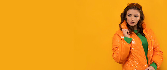 Winter clothes on pretty brunette with long hairs on isolated orange background.