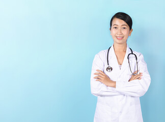 Asian medical doctor woman with stethoscope crossed arms isolated on light blue background.
