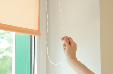 Woman's hand lowers or raises roller blinds in her office