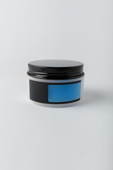 Cream container with empty blue label, mock up template on white background. Face and body skin care cosmetics, vertical shot, copy space