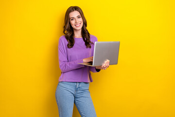 Photo of positive nice girl toothy smile hold use wireless netbook isolated on yellow color...