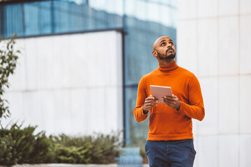 Man holding a digital tablet looking up in the sky