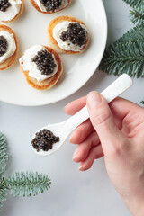 Black caviar appetizers mini pancakes on a christmas decorated white background