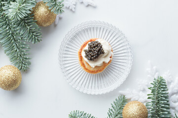 Black caviar appetizers mini pancake on a christmas decorated white background