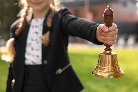 A small bell in the girl's hand on a neutral background, close-up