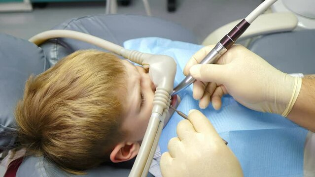 Nitrous oxide in dental clinic while treating young patients with milk teeth. Relaxation of patient before surgical or dental procedures. Child lying in dental chair with inhalation sedation. 4 k