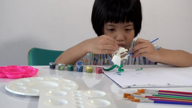 Chinese girl paint blue color to the leg of dragon figure at table