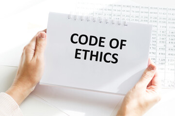 Man hands holding tablet with text Code of Ethics at workplace. Businessman working at desk with documents