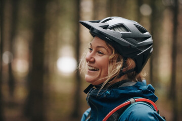 Laughing young woman mountain biking with friends in a forest