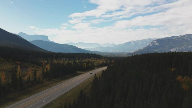 Fascinating Scene of Cars driving on the Yellowhead Highway 5 with the Canadian Rocky Mountains in the background on a Cloudy Day in fall in Alberta , Canada