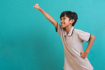 Little Asian boy doing a Superhero gesture to fly, isolated on green background. Creative kid concept.