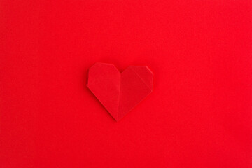 Obraz premium Red origami heart on red background