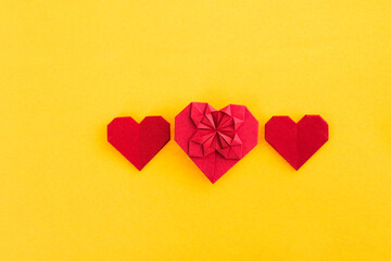 Red origami hearts on yellow background