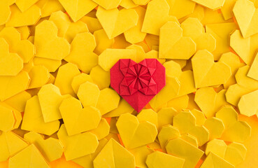 Red origami heart on yellow origami hearts