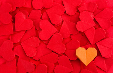 Orange origami heart on red origami hearts